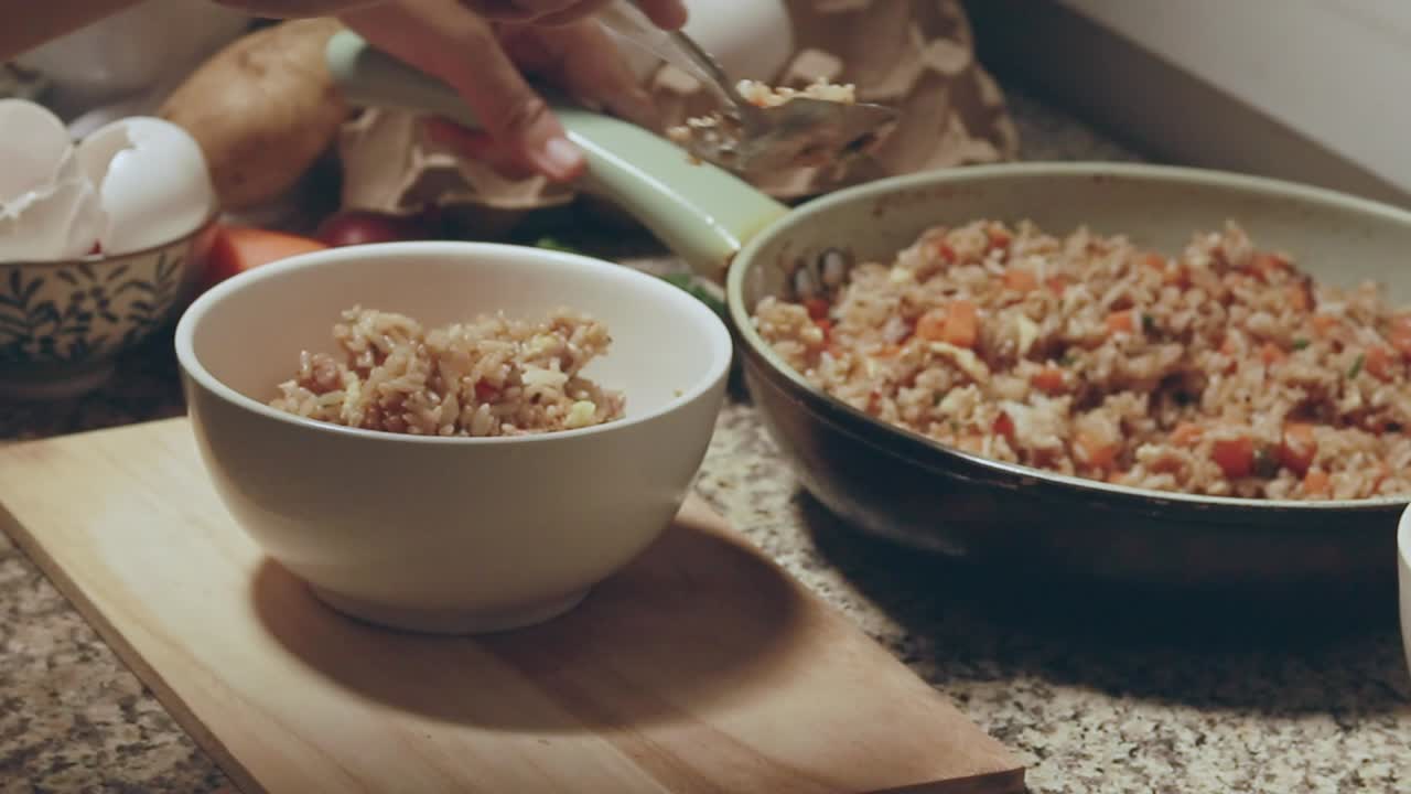 Serving fried rice into a white bowl showing a candid daily life moment of home cooking and slow living