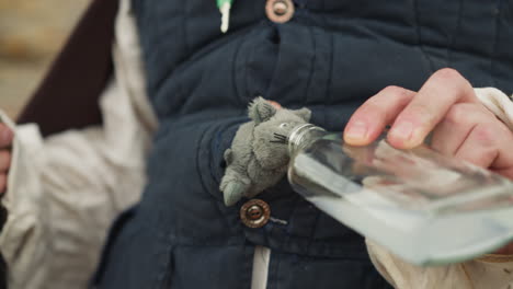 el hombre le da una bebida mágica de una botella de vidrio al ratón de juguete