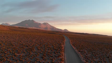 Aerial-cinematic-shot-of-a-dirt-road-at-sunset-in-the-Atacama-Desert,-Chile,-South-America