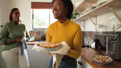 laughing and holding freshly baked pie, friends in kitchen together