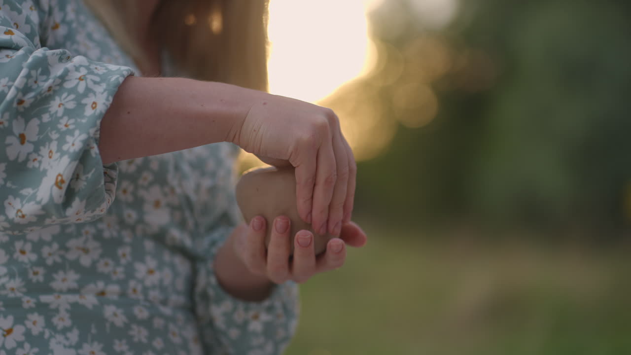 Women's hands close-up sculpt an object from clay in nature outdoors in the park in the evening at sunset.