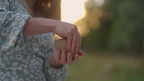Women&#039;s hands close-up sculpt an object from clay in nature outdoors in the park in the evening at sunset.