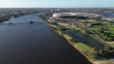 drone estableciendo una toma del río swan con el moderno puente matagarup y el estadio optus en la ciudad de perth durante la hora dorada