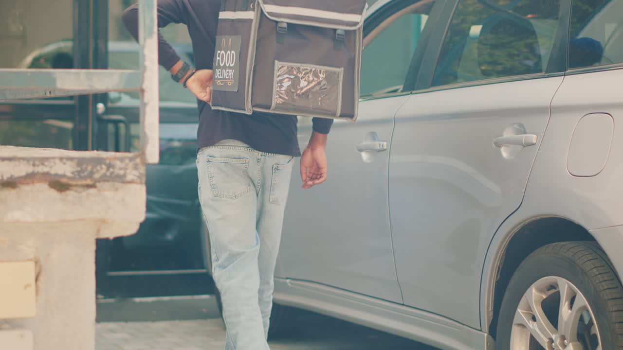 A person placing a food delivery box in a car