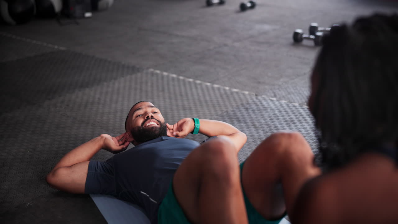 hombre y mujer haciendo abdominales en un gimnasio