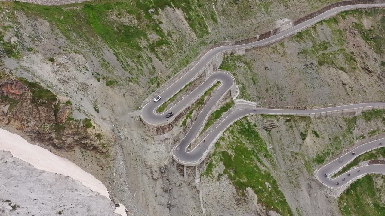 Top-down drone shot reveals winding Stelvio road through steep alpine cliffs