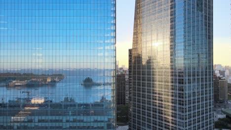 aerial dolly out of puerto madero docks reflected in window glass skyscrapers at sunset, buenos aires