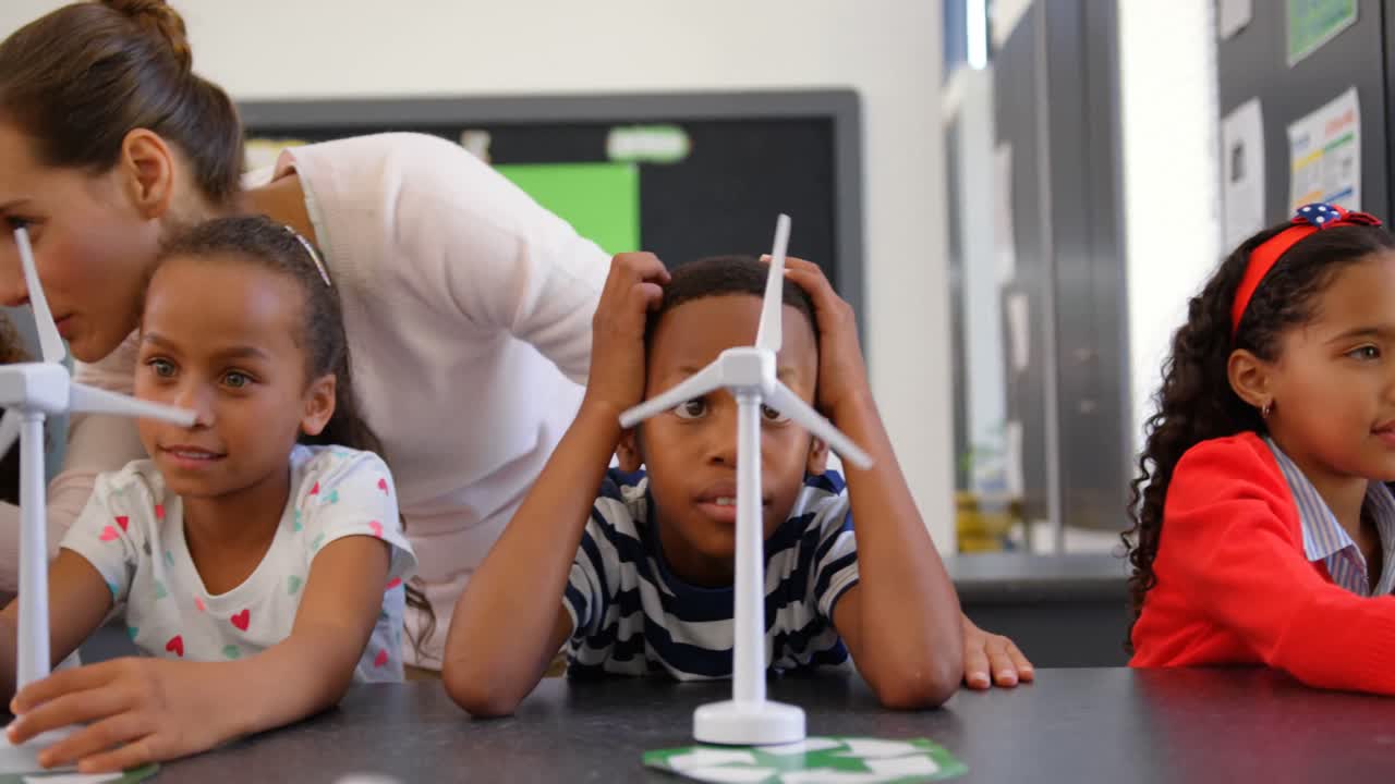 Front view of Caucasian female teacher teaching schoolkids about windmill in the classroom 4k