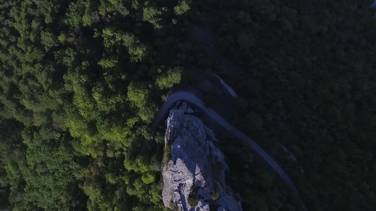 vista aérea de un bosque montañoso con una carretera sinuosa y un acantilado