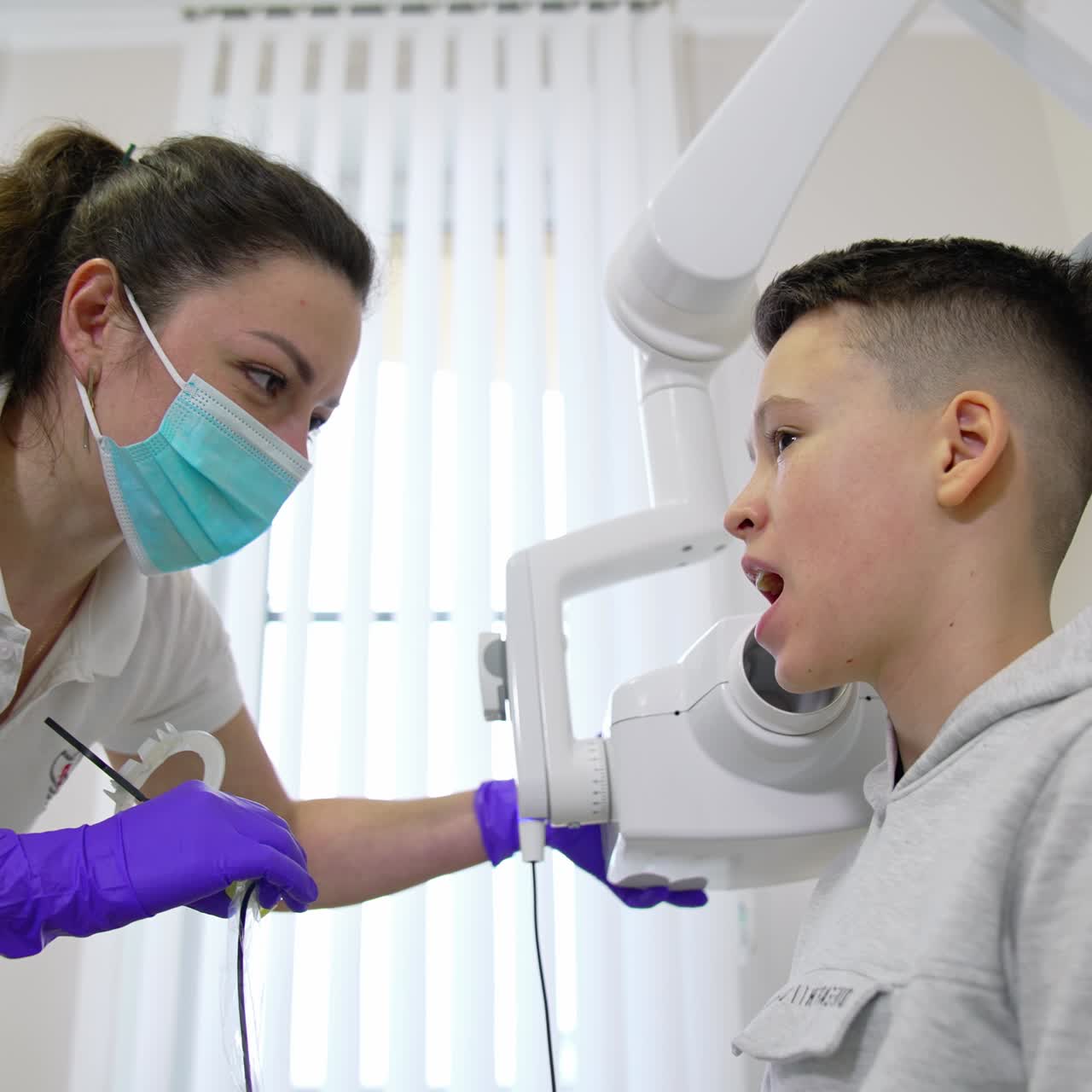 Esecuzione di una radiografia dei denti per un ragazzo in clinica odontoiatrica. Dentista che scansiona la mascella con i raggi X per un ragazzo preadolescente. Controllo orale dei denti ed esame preventivo