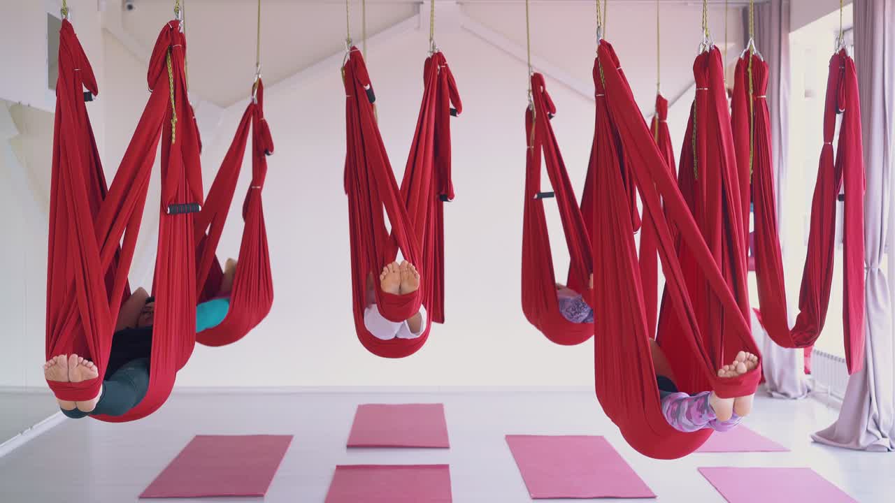 편안한 여성 그룹은 큰 빨간 공중 플라이 요가 하마크에 누워 있습니다.