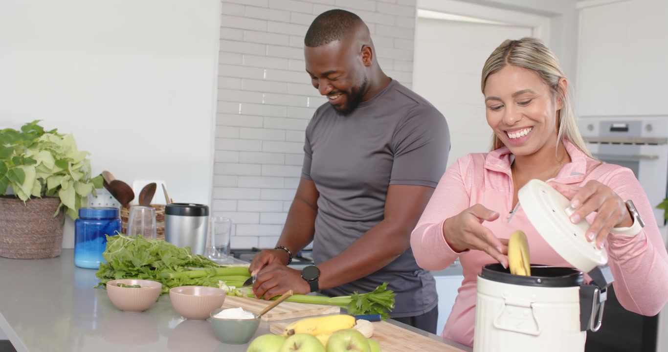 Casal afro-americano picando e fatiando depois que a mulher abre um recipiente branco, preparando a refeição.