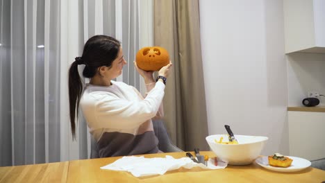 Foto-De-Una-Mujer-Joven-En-Casa-Que-Muestra-Una-Calabaza-Tallada-Para-La-Decoración-De-Halloween