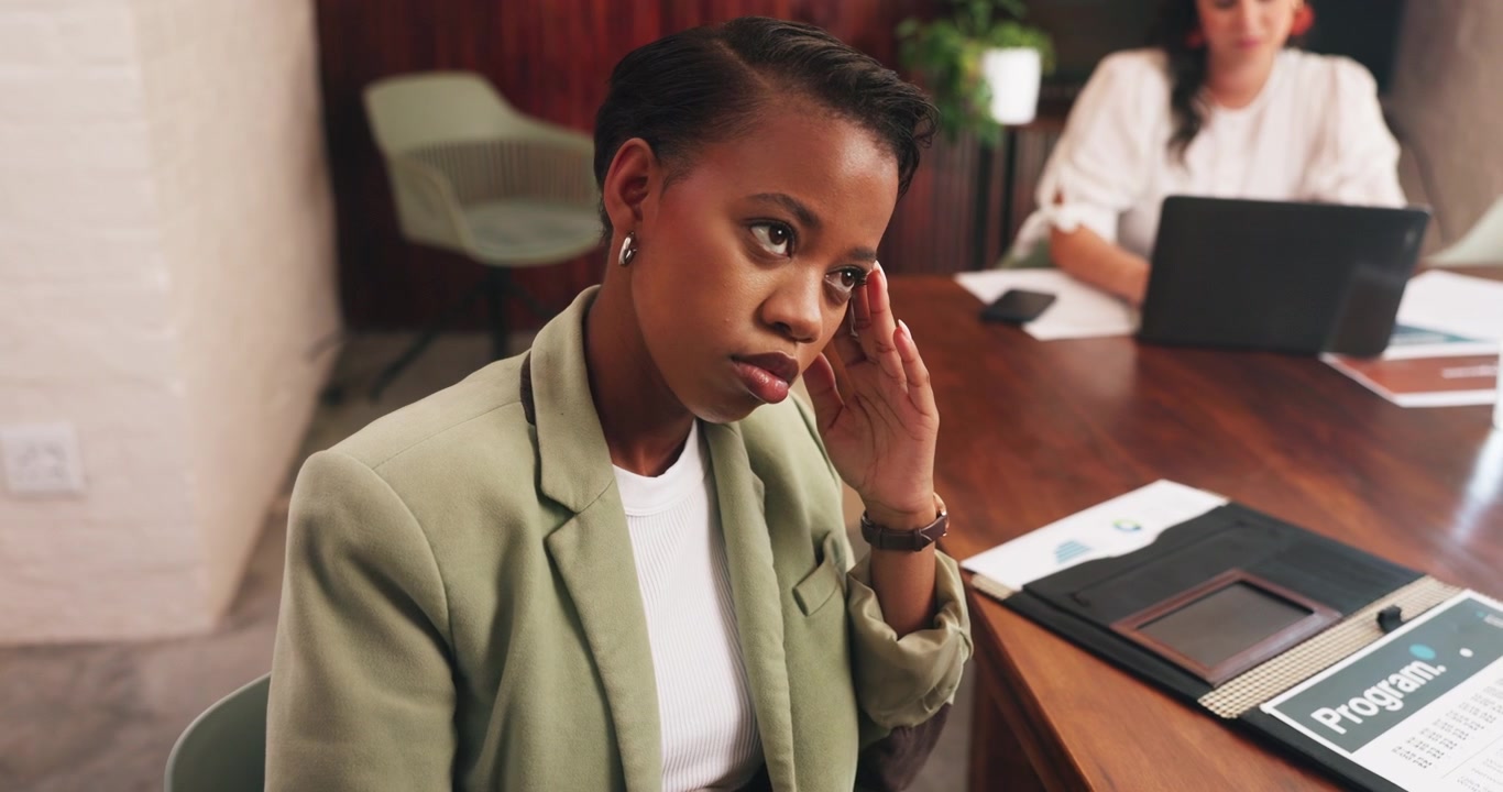 Stressed Businesswoman Sitting at Office Desk During Meeting