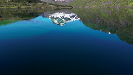 summer in the fjords near husjord, norway: reflected mountains on serene waters