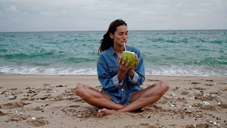 mujer bebiendo agua de coco en la playa