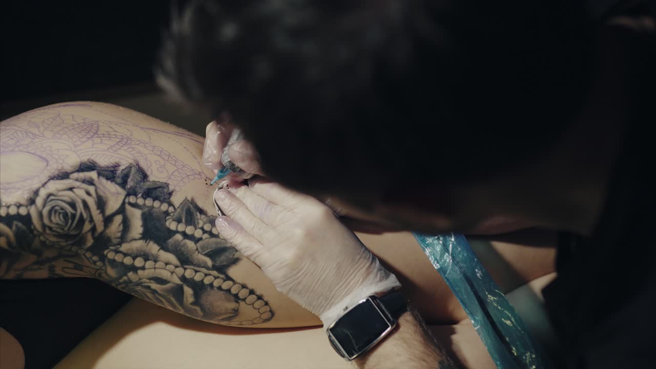 татуировщик работает над татуировкой на ноге