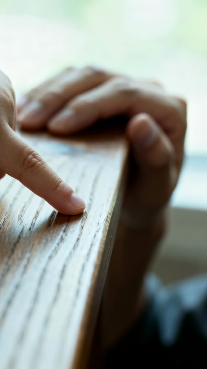 Vertical video: First touch, kid finger feeling wood sill at window, adult hand resting dark sleeve