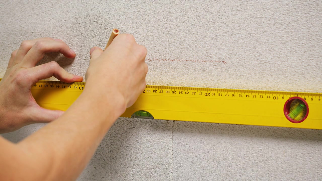 Hands Using Spirit Level to Mark a Straight Line on a Wall