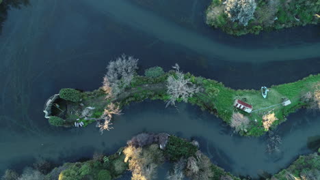 Smooth-tracking-shots-above-small-cabin-and-boat-docked-on-shoreline-on-a-winters-afternoon