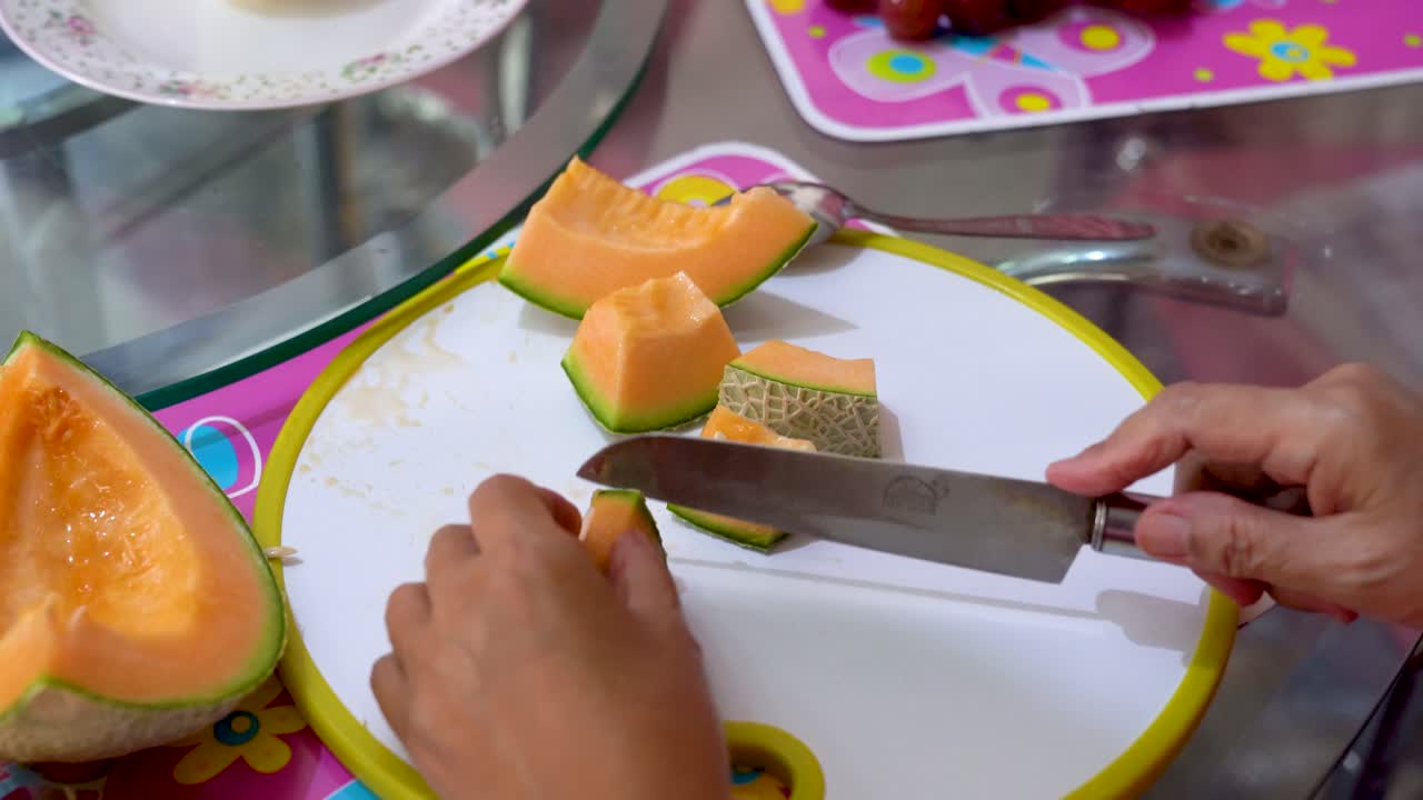 Hands of woman slicing golden melon on cutting board, close up view