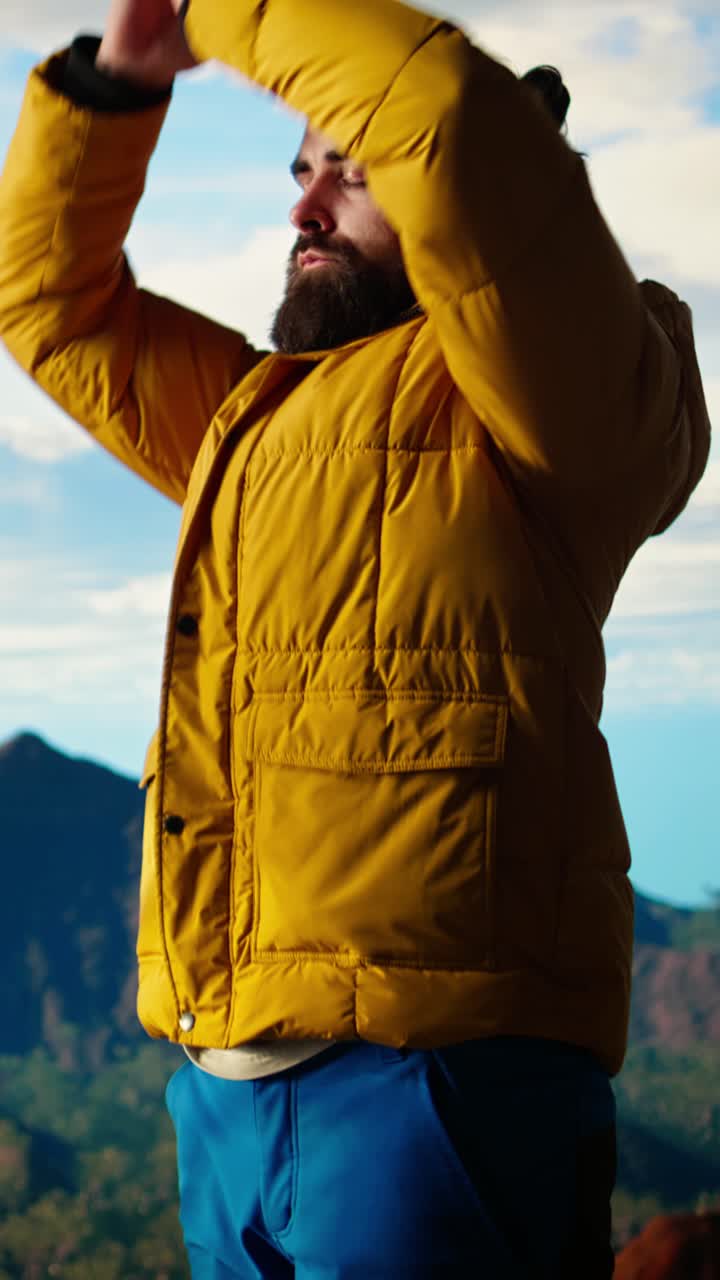 Uomo barbuto che medita sulla vetta della montagna con le mani giunte in preghiera