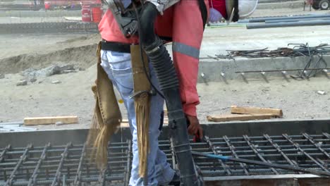 inclinado hacia arriba, un hombre aspirando en medio de una gran construcción usando equipo de seguridad