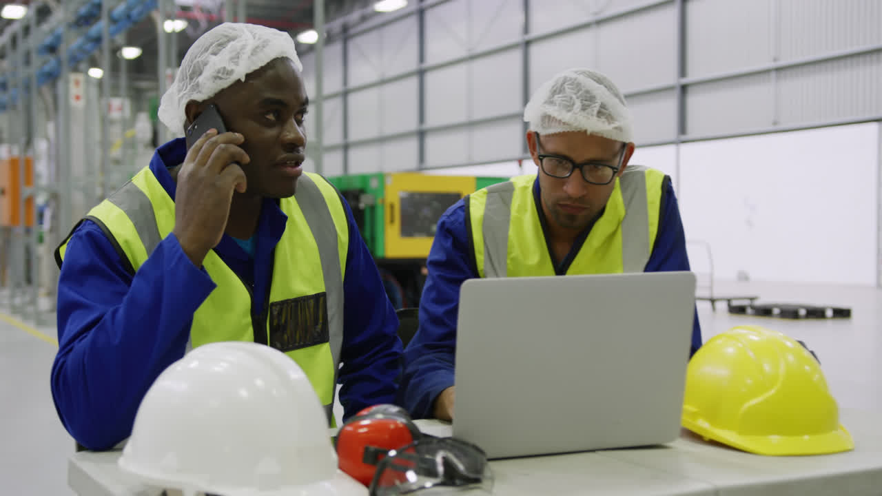 Warehouse workers using laptop in factory