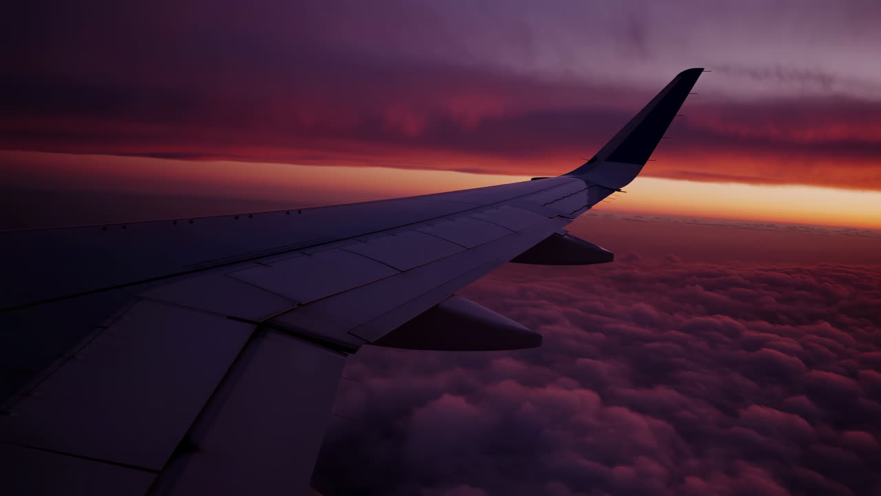 Airplane wing at sunset over clouds