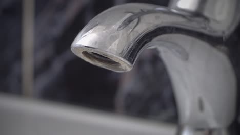 water is leaking from broken chrome tap drop by drop. the close view of water dripping from shiny tap, faucet. plumber needed, loop background