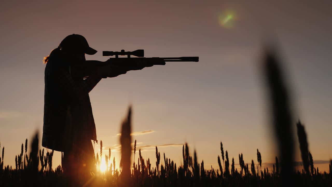 Il cacciatore mira con un fucile dotato di mirino ottico, è in piedi in un luogo pittoresco al tramonto 4.