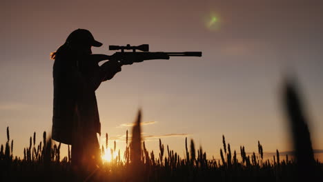 the hunter is aiming from a rifle with an optical sight it stands in a picturesque place at sunset 4