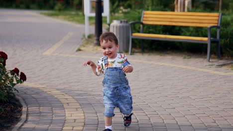 happy running kid in a jeans romper. smiling child having fun outside in summer.