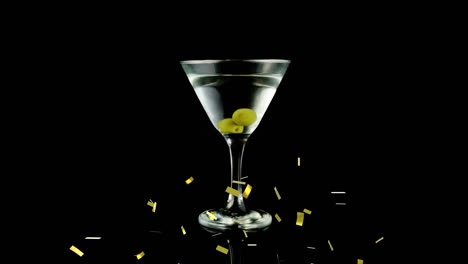 animation of gold confetti falling over glass of wine with olives on black background