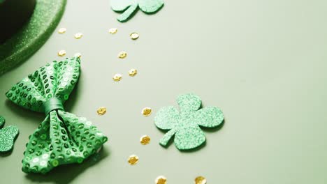 video of saint patricks day green shamrock, hat and bow tie with copy space on green background