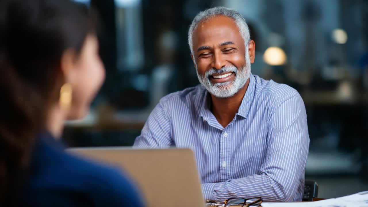 A Warm Conversation: Smiling Older Man Engages with Woman in Professional Setting, Radiating Positivity and Connection During Meaningful Interaction at Office Environment with Soft Lighting