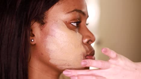 a female makeup artist applying gold makeup to a black african-american model. the concept of beauty and makeup