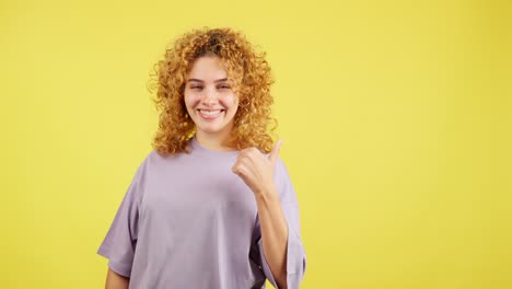 smiling young woman with curly hair posing on yellow background