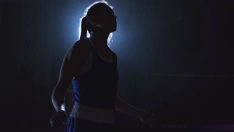 woman boxer jumping on skipping rope in the boxing hall with a ring