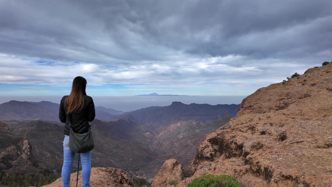 Donna in piedi su una cima di montagna, che si gode la vista panoramica della valle dal Roque Nublo a Gran Canaria, Isole Canarie