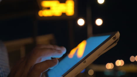 man working with touch pad on bus stop at night