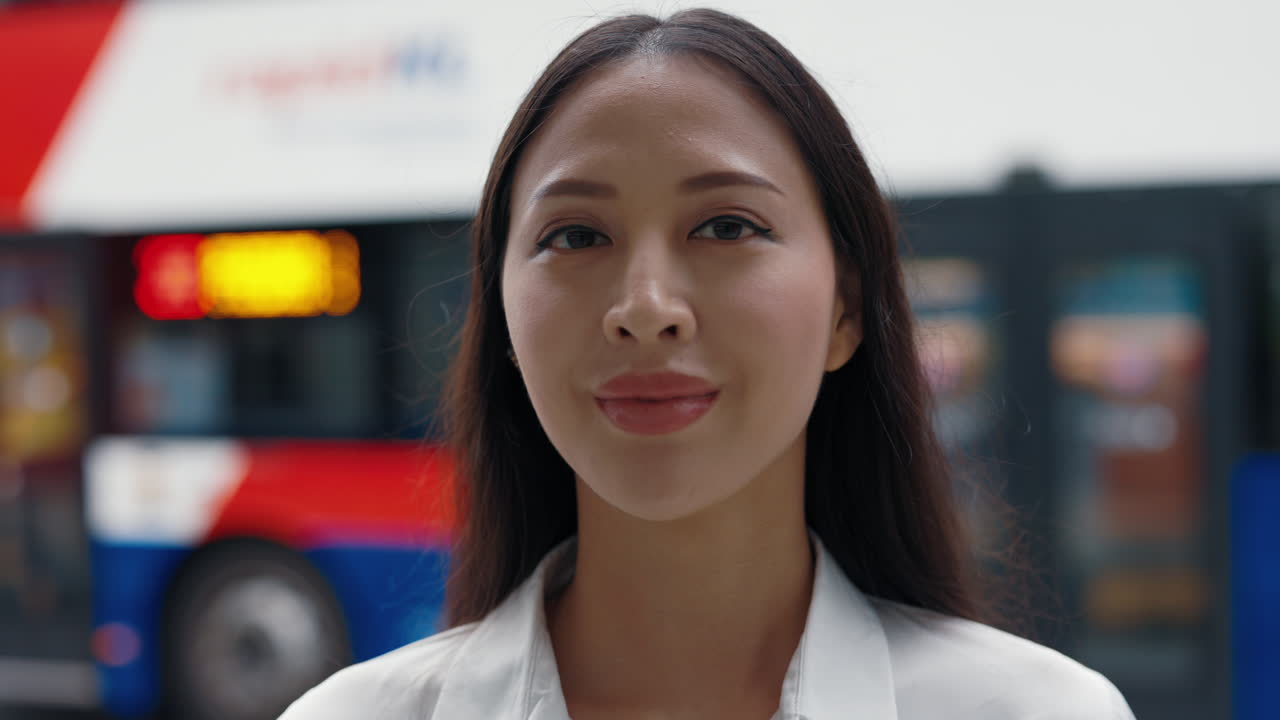Donna asiatica sorridente di fronte all'autobus