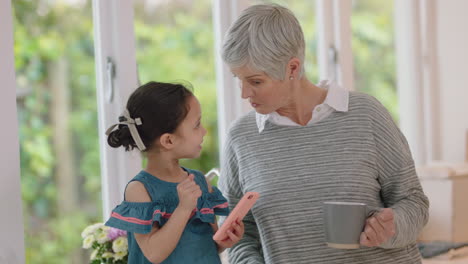 cute little girl showing grandmother how to use smartphone teaching granny modern technology intelligent child helping grandma with mobile phone at home