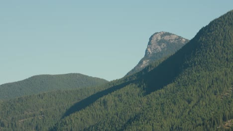 Una-Larga-Toma-De-Teleobjetivo-Del-Paisaje-De-La-Cordillera-Del-Corazón-Cubierto-De-Bosques-Contra-Un-Cielo-Azul-De-Verano-En-El-Parque-Nacional-Banff,-Canadá