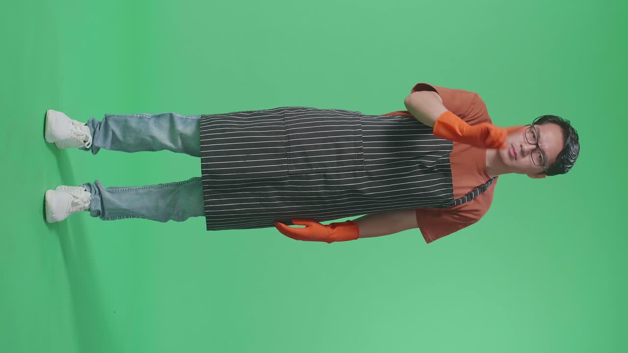 Full Body Of Disagree Asian Male Housekeeper With An Apron Wagging His Finger While Standing In The Green Screen Studio