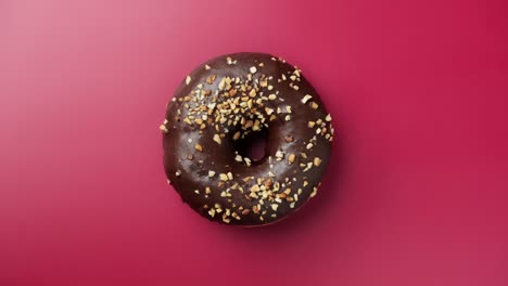 tasty chocolate donut rotating at pink background. delicious donut.