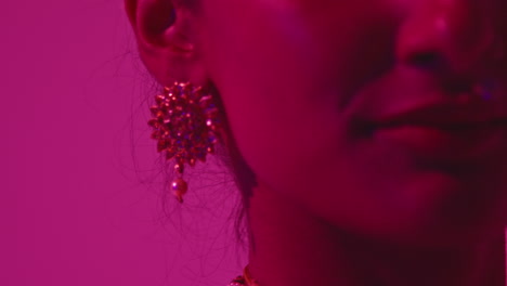 close up on jewellery of female kathak dancer performing dance wearing traditional indian dress against purple background