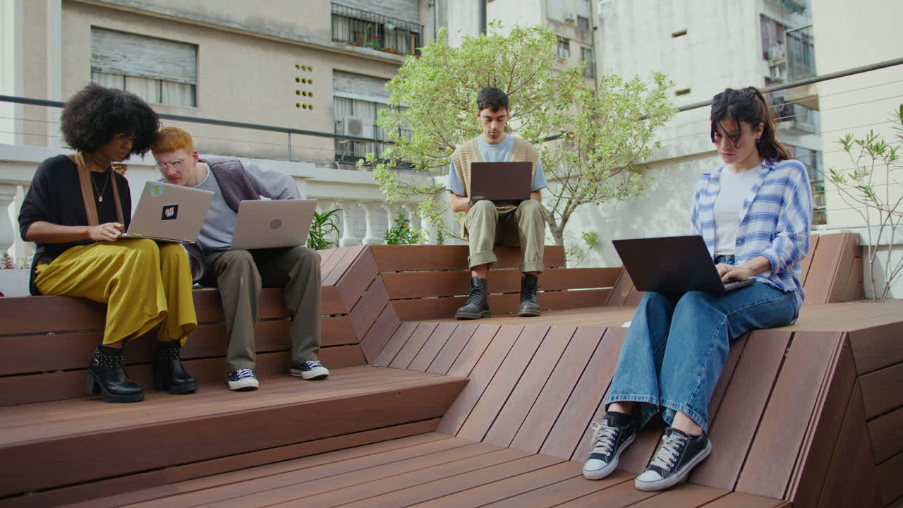 Young People Using Laptops and Working Remotely Outdoors in the City