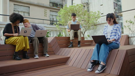 young people using laptops and working remotely outdoors in the city