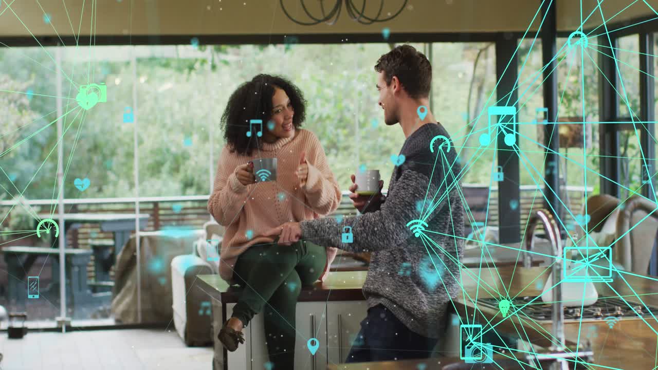 animación de la red de iconos de los medios sobre una feliz pareja biracial tomando café hablando en casa